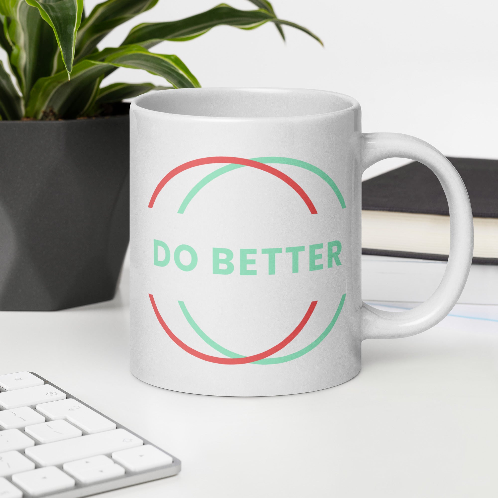 Scaling Better do better white glossy mug with colorful circular design on desk near keyboard and plant